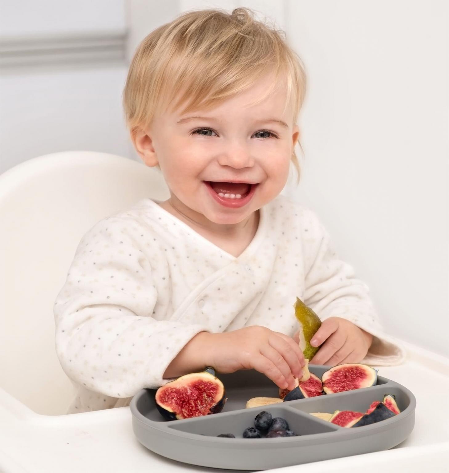 baby eating fruit from silicone plate