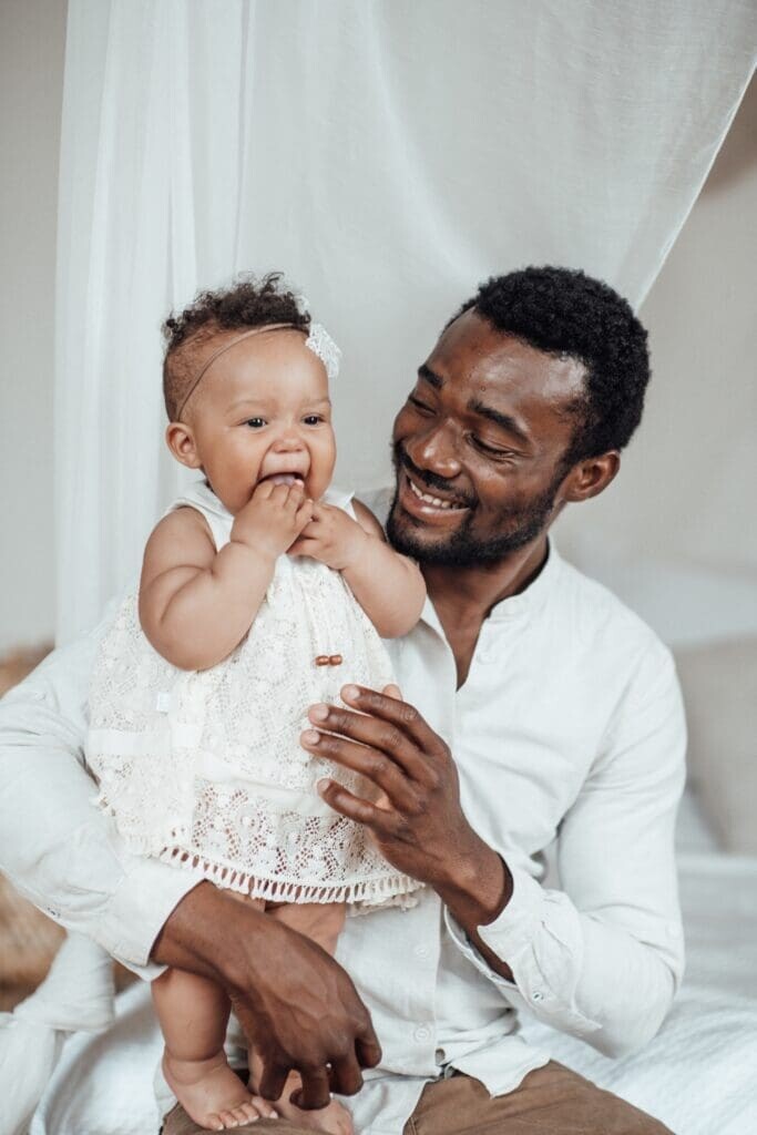 Happy candid black ethnicity dad spending time together with toddler ebony daughter in apartment